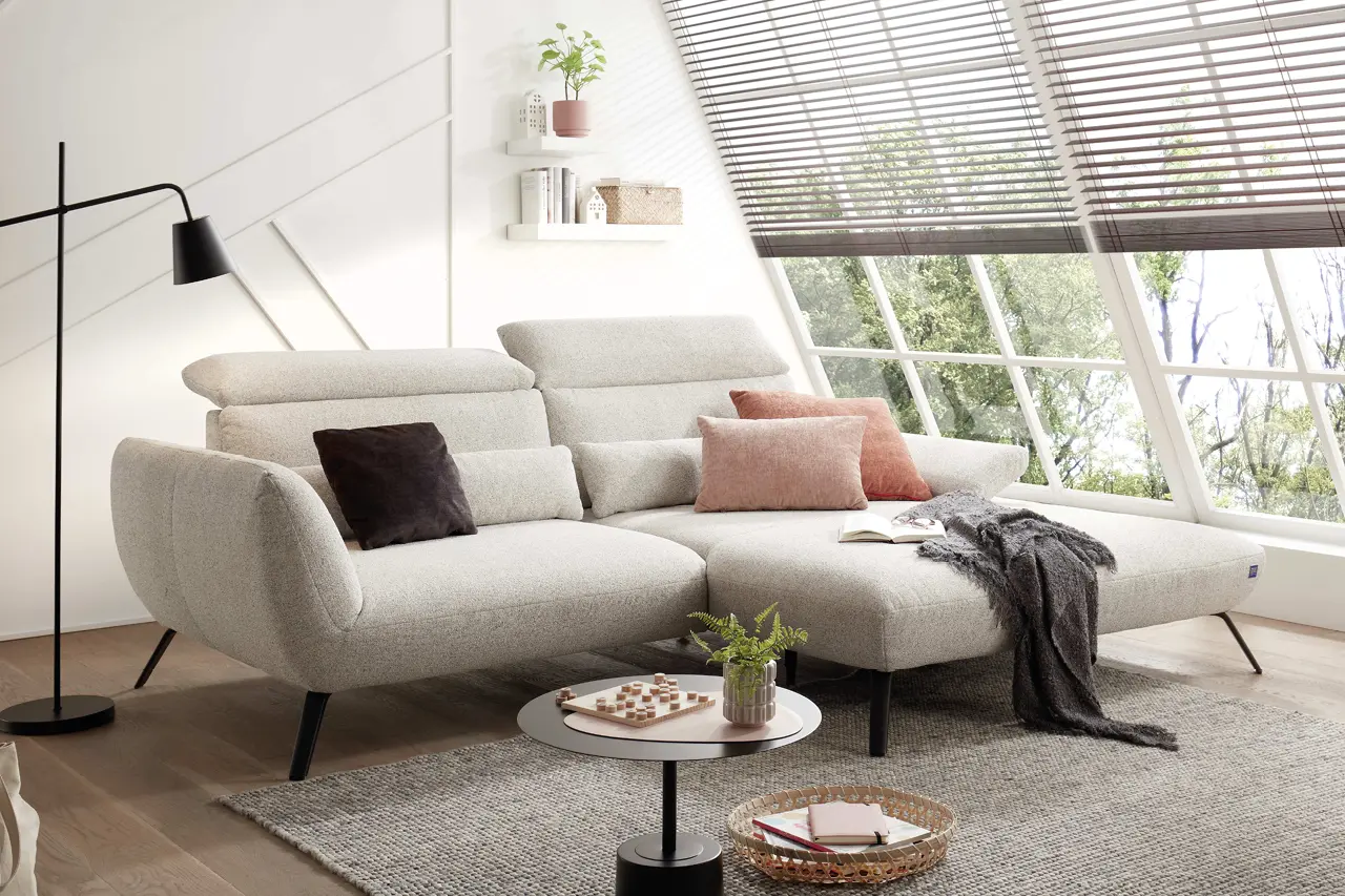 Graues Sofa Set mit zwei Sofas und Hocker, Couchtisch aus Glas auf Teppich im Wohnzimmer mit Stehlampe und Bild an der Wand